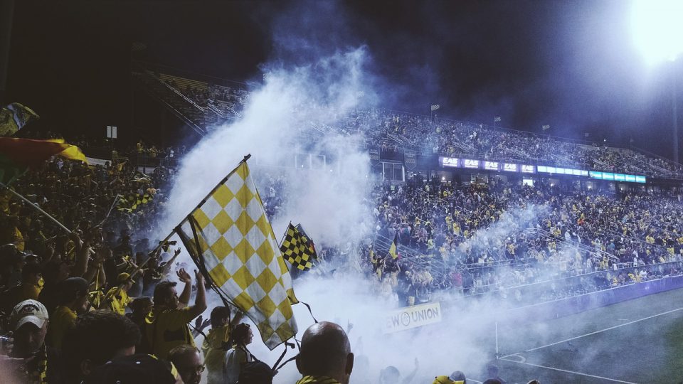 football fans with flags and smoke in a stadium